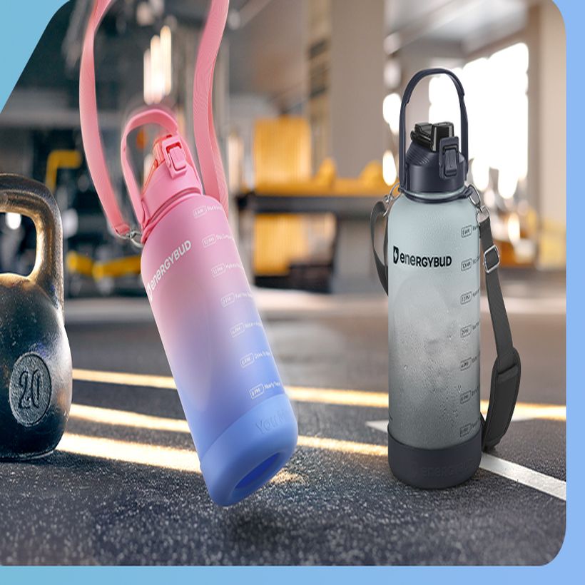 Two EnergyBud bottles standing on a gym floor beside a kettlebell