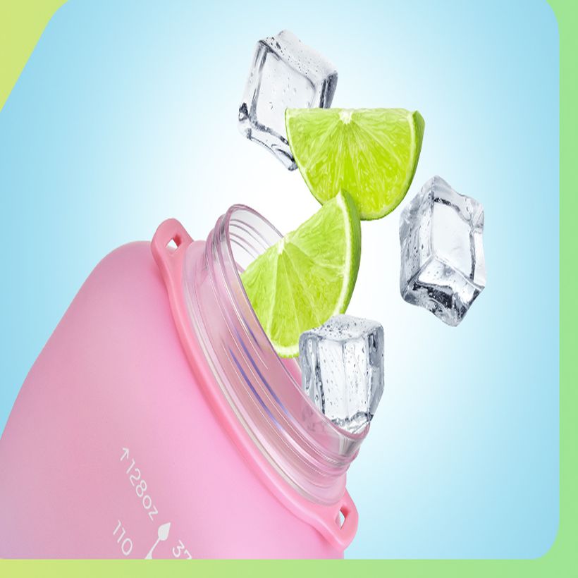 Ice cubes and lime wedges falling into the wide neck of the bottle