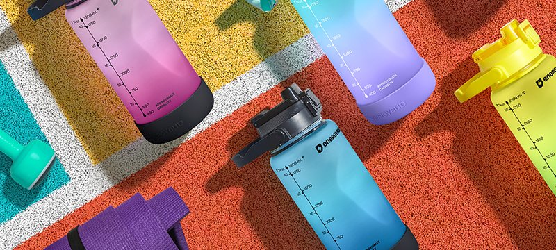 EnergyBud half gallon bottles in pink, violet, lime and blue laid out on a running track